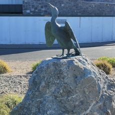 Metal sculpture of Cormorant bird on a stone base.