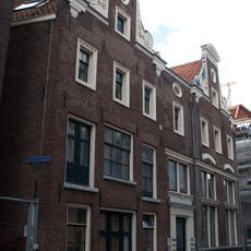 Pand met twee halsgevels met gebeeldhouwde vleugelstukken en gebogen frontons en met gewijzigde onderbouw