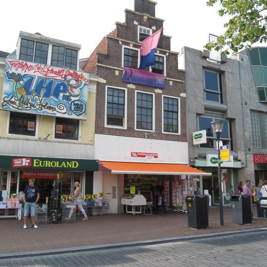 Pand onder zadeldak tegen trapgevel versierd met blokken in de bogen en strekken boven de vensters