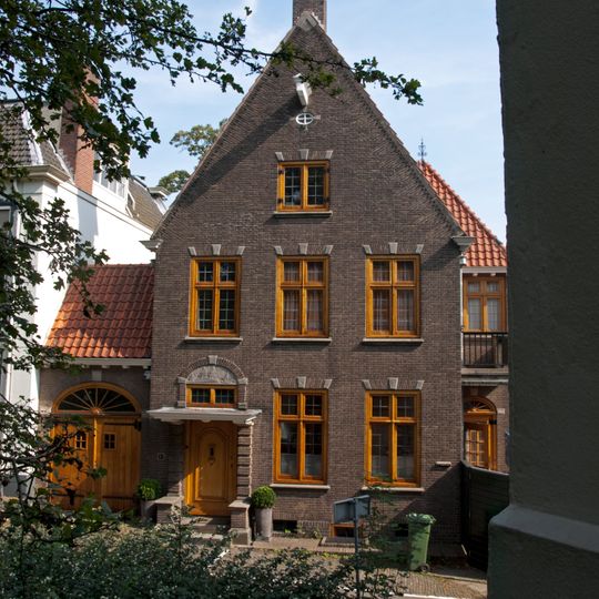 Gepleisterd pand zonder verdieping met door pannen gedekt zadeldak, dat links aansluit tegen een puntgevel