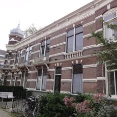 Blok met woonhuis, beneden- en bovenwoning met een door een eenvoudig smeedijzeren spijlenhek omzoomde voortuin