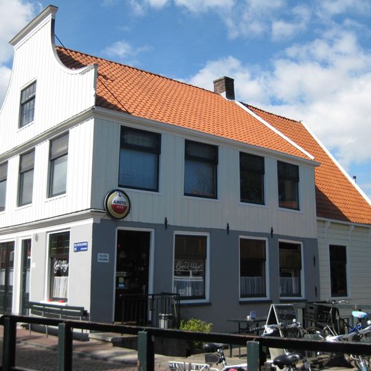 Houten dijkhuis met halsgevel uit 19de eeuw, voorste deel in 19de eeuw met een verdieping verhoogd, nu café 't Sluisje