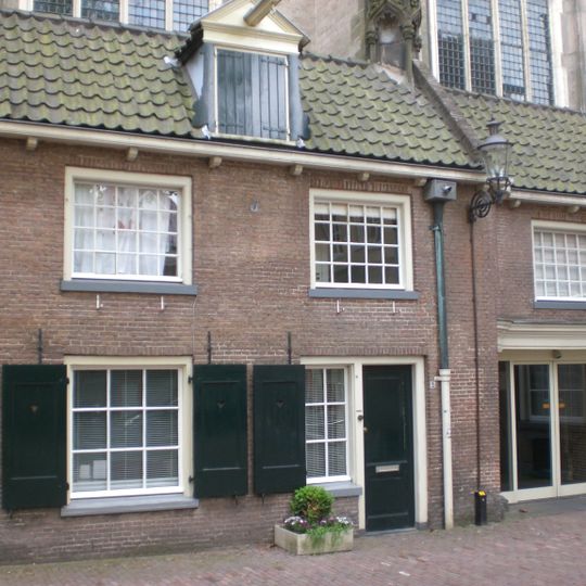 Tegen kooromgang van de kerk aan gebouwd huis met dak