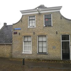 Hoekpand aan de haven met ingezwenkte afgeknotte gevel aan de Commandeurstraatzijde en aan de havenzijde erker en zijtuin