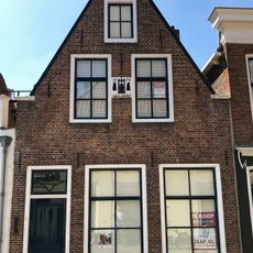 Pand onder zadeldak tegen smalle puntgevel, afgedekt door houten lijsten