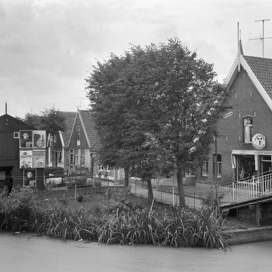 Pand onder zadeldak. Geverfde gevel met zesruits vensters waarboven een houten geveltopbeschieting met gesneden windveren