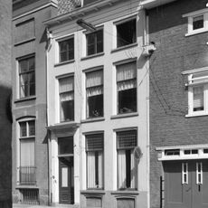 Gepleisterde lijstgevel voor huis onder schilddak met dakkapel