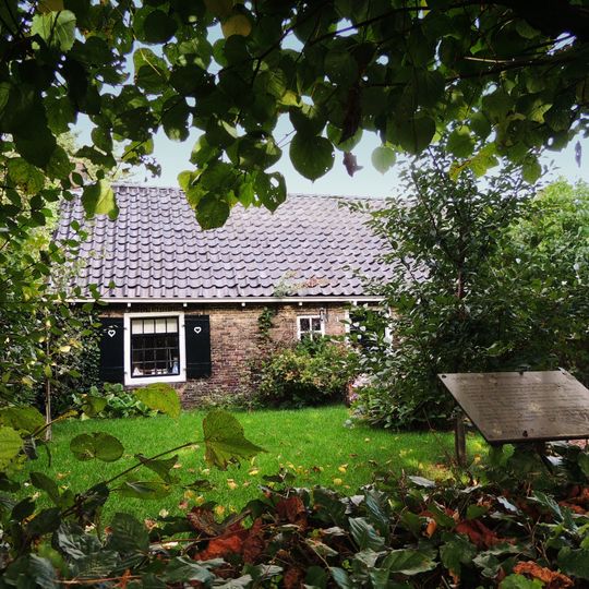 Eenvoudig pand met twaalf- en vierruitsvensters onder laag zadeldak met schoorstenen tussen topgevels