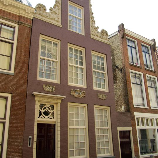 Pand onder zadeldak tegen rijk met beeldhouwwerk versierde halsgevel