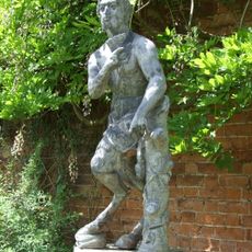 Statue of Pan circa 35 metres south east of the Stables