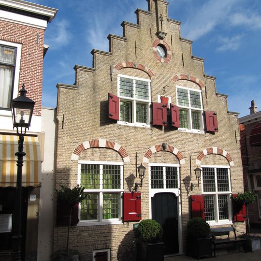 Pand met trapgevel met maskerkoppen als sluitstenen boven de vensters,