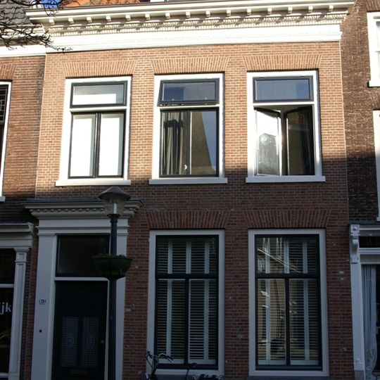 Huis met eenvoudige gevel onder zeer rijk gesneden lijst