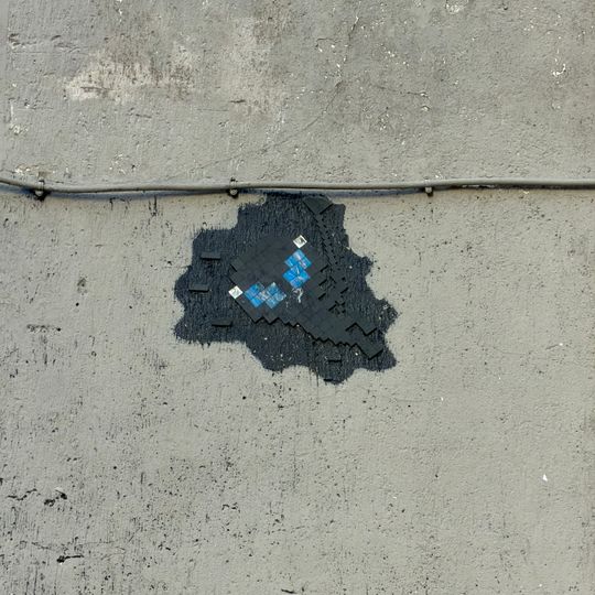 Extraterrestre gris, yeux bleu, qui fait de la tirolienne sur le cable electrique qui passe sur le mur de l'immeuble