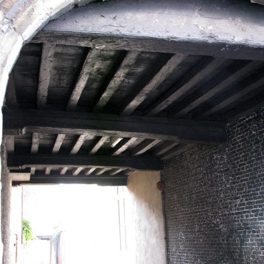 Gotische korfboog aan de zijde van de Beursstraat doorgang afsluitend bewerkte sleutelstukken. De boog ontspringt op gebeeldhouwde draagsteentjes . Twee schamppalen