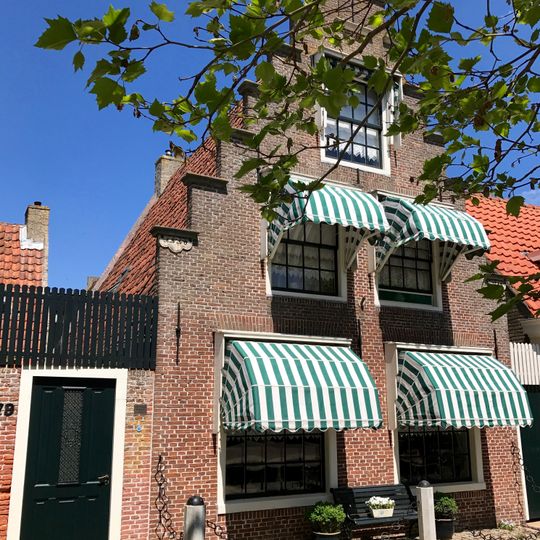 Pand onder zadeldak met dwarsbouw aan achterzijde en puntvormige voorgevel met beitelingen