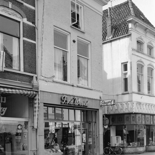 Hoekpand met geverfde gevel met kroonlijst en jongere winkelpui