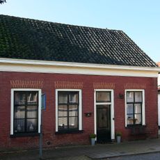 Dwarshuis van alleen begane-grond met zadeldak tussen puntgevels. Rood gesausd metselwerk met gele vensterstrekken