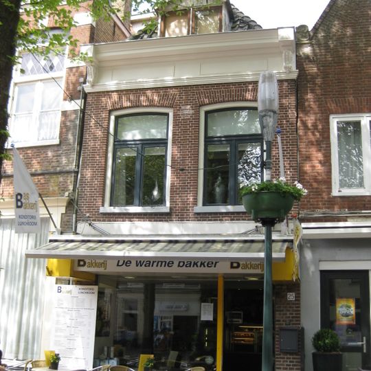 Pand onder zadeldak met eenvoudige gevel afgesloten door lijst met consoles en verdiepte velden