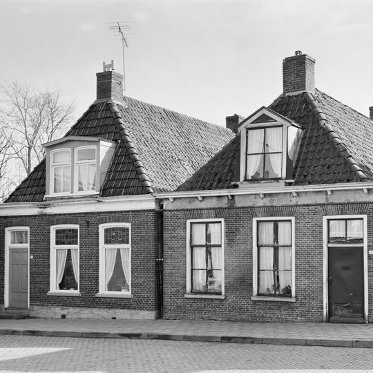 Eenvoudig pand met zesruitsvensters en goot op blokken onder zadeldak met voorschild en dakkapel