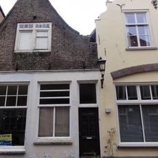 Huis met ingezwenkte halsgevel, waarlangs uitgemetselde rollaag. Een geheel met nr 18