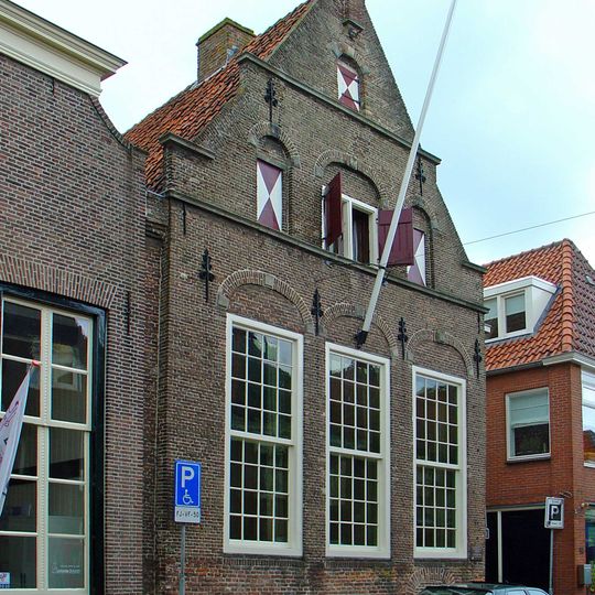 Huis met gerestaureerde puntgevel met zandstenen waterlijsten en afdekplaten en uitgekraagde toppilaster op zandstenen console met engelenkopje