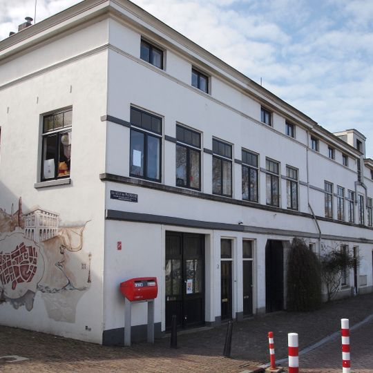 Langgerekt pand, vrijwel geheel gepleisterd, met verdieping en mezzanino onder flauwhellend, met pannen gedekt schilddak