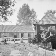 Eenvoudig verdiepingloos pand gedekt door twee dwarse zadeldaken tussen houten topgevels