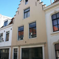 Huis met gepleisterde trapgevel. De treden afgedekt met natuurstenen platen. Eenvoudige voordeurlijsting