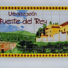 Azulejo con una imagen de la urbanización Fuente del Rey y la propia Fuente del Rey con la sierra de Mijas al fondo.