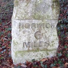 Milestone, 30yds E of 2 brick houses with central chimneys