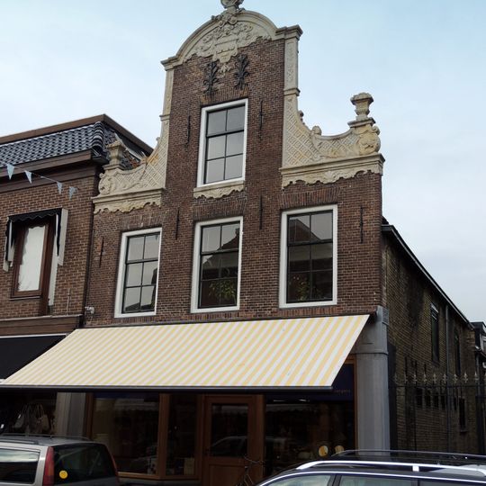 Pand met zadeldak tegen halsgevel met gebeeldhouwde klauwstukken en bekroning in de Friese Lodewijk XIV-stijl