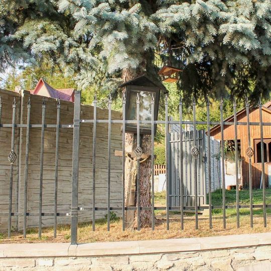 Obrázek a dřevěný kříž v Hrabenově v zahradě za plotem