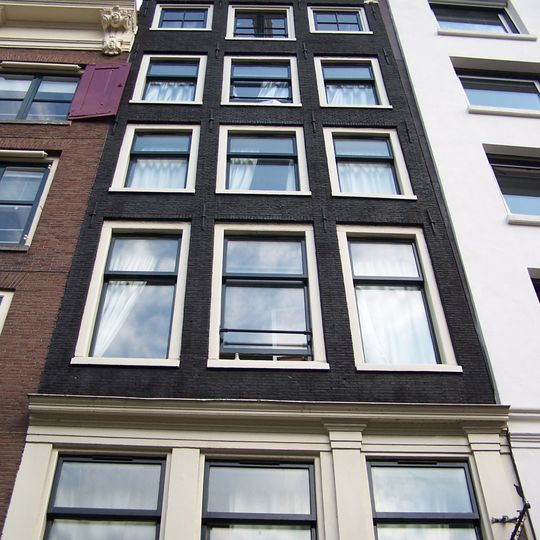 Pand met gevel onder rijk gebeeldhouwde cirkelvormig verhoogde zandstenen lijst