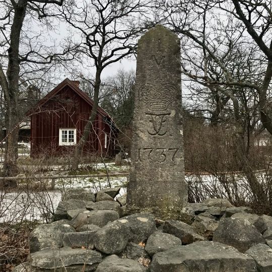 Helmilstolpe i sten från 1737 med krona och kungamonogram , Skansen