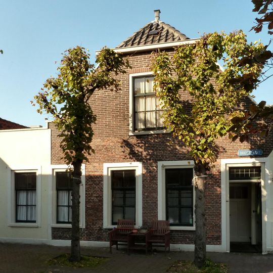 Huis met topgevel, van eenvoudige doch harmonische architectuur, goede proportie's. Specifieke stedebouwkundige ligging