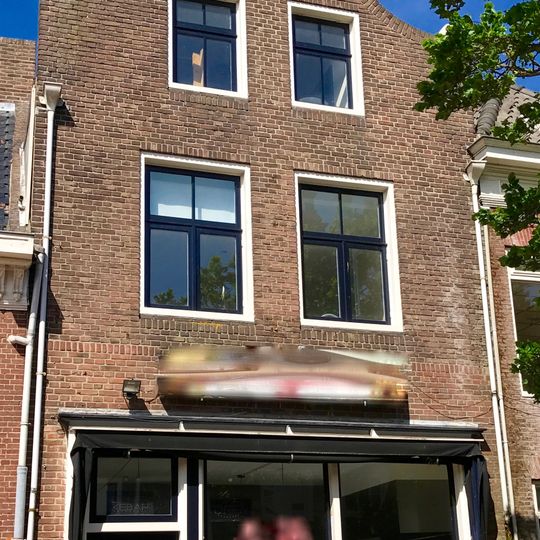 Hoog pand onder zadeldak tussen klokvormige voorgevel met aanzetkrullen en gezwenkte lijst en achtertopgevel