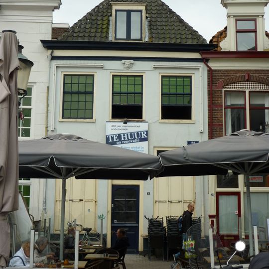 Huis met eenvoudige gepleisterde lijstgevel met gebeeldhouwde satirekop