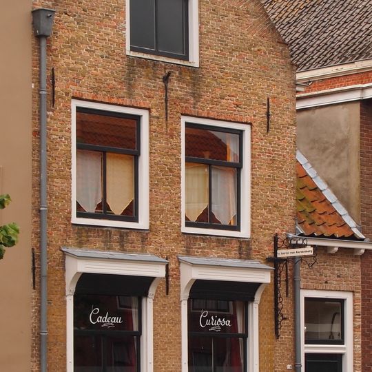 Onderkelderd pand met tuitgevel met vlechtingen