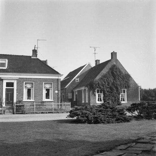 Eenvoudig pand onder zadeldak tegen brede topgevel met hoge schuur onder zadeldak