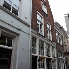 Huis onder zadeldak en met topgevel waarin schuiframen en houten pui met witte roedenverdeling