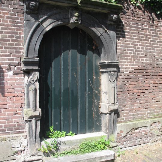Natuurstenen tuinpoort met gebeeldhouwde sluitsteen, zijposten en kroonlijstconsoles