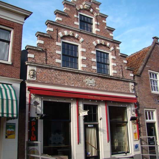 Huis met houten puntgevel boven een pui met een gebogen hoekvenster en aan weerszijden van de ingang pilasters