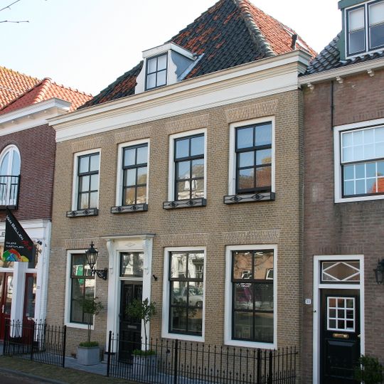 Huis onder schilddak en met lijstgevel in gele baksteen