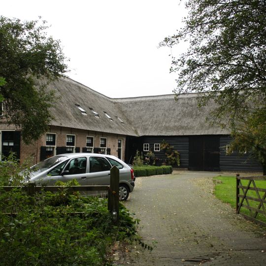 Boerderij met korte gevel met toppinakel en haaks aangebouwde houten bijschuur
