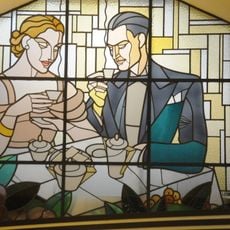 Vitral Arte Deco que mostra um casal sentado à mesa a consumir café.