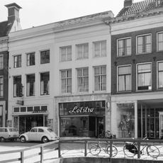 Pand met verhoogde voorbouw onder dwarskap tussen topgevels bekroond door schoorstenen met borden