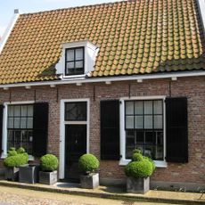 Laag huis onder zadeldak, rechte gootlijst. Poort