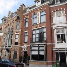 Pand in neo-renaissance trant met in de gevel vensters met geblokte ontlastingsbogen. Houten erker met snijwerk en balustrade. Kroonlijst, waarboven dakkapellen