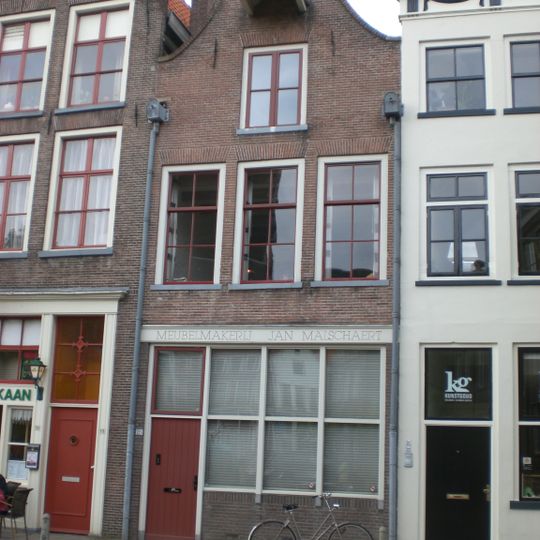 Huis met klokgevel voorzien van half cirkelvormige bekroning met natuurstenen lijst