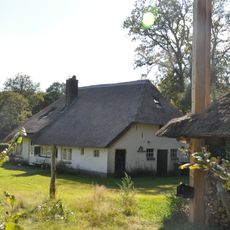 Boerderij met hoog rieten wolfdak, vensters met kleine roedenverdeling in de ramen en luiken. Mooie roedenberg